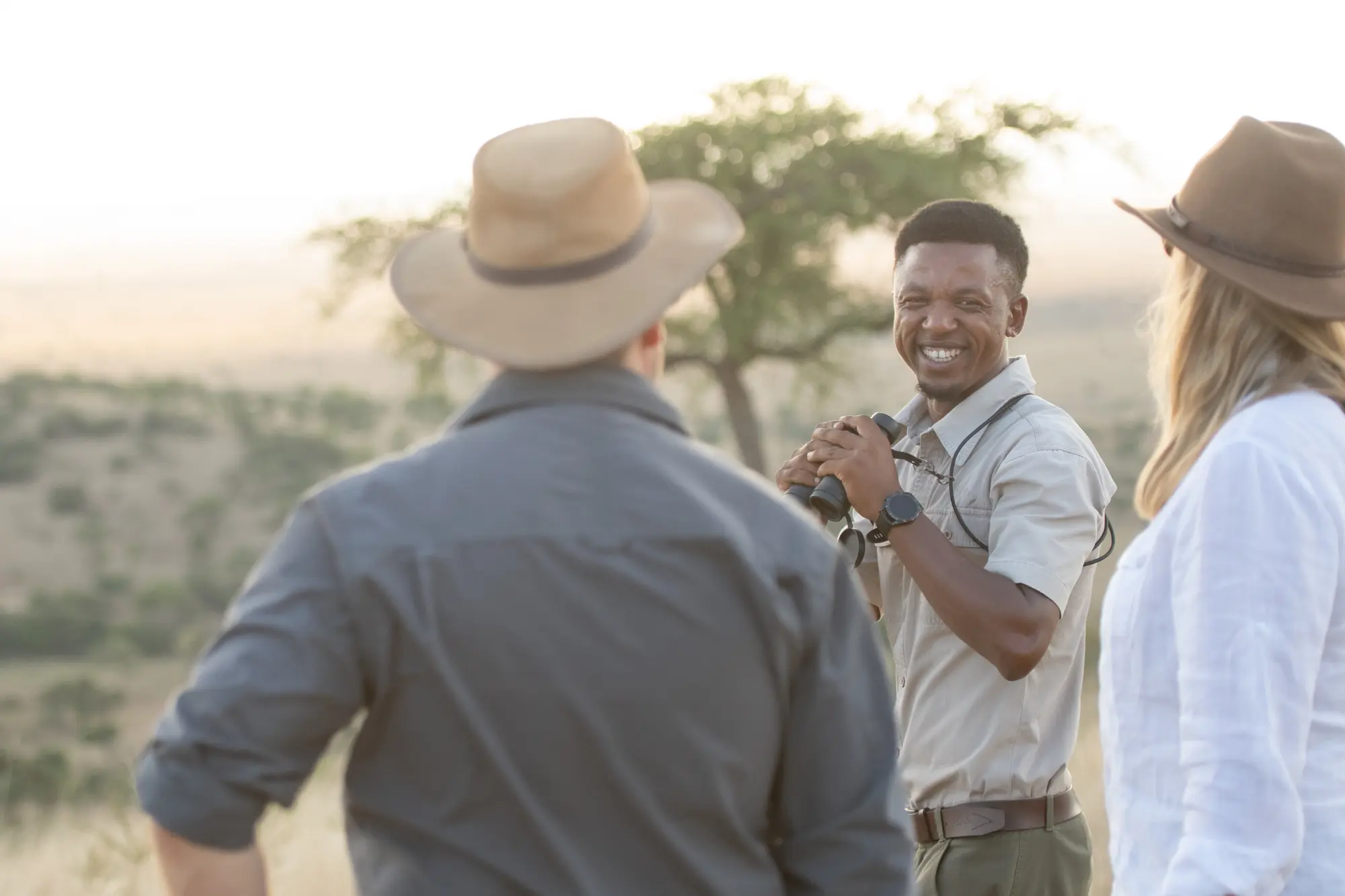 AGE guide with binoculars engaging with guests on the Tanzania plains